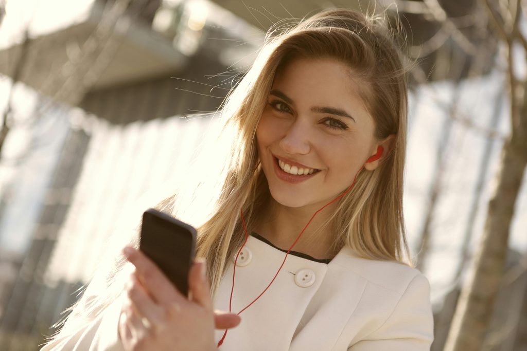 Happy young woman smiling while holding her fully charged smartphone, expressing joy and satisfaction.